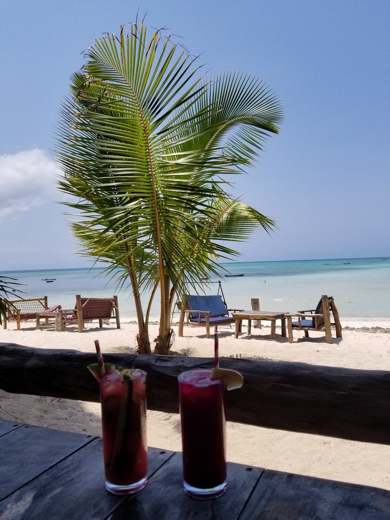 two drinks on a table on a beach