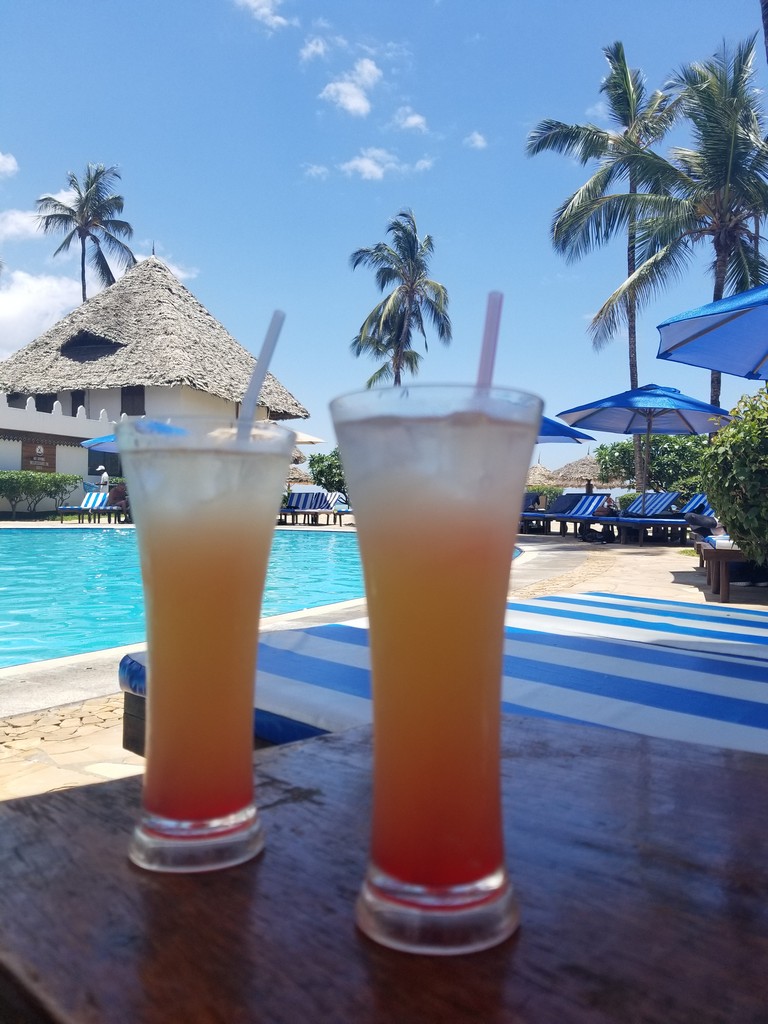 two drinks on a table by a pool