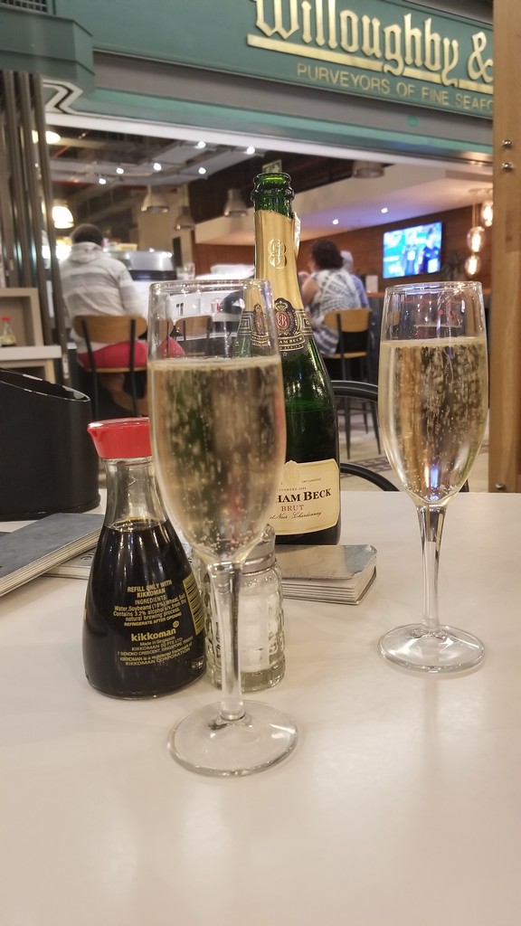 a glass of champagne and a bottle of soy sauce on a table