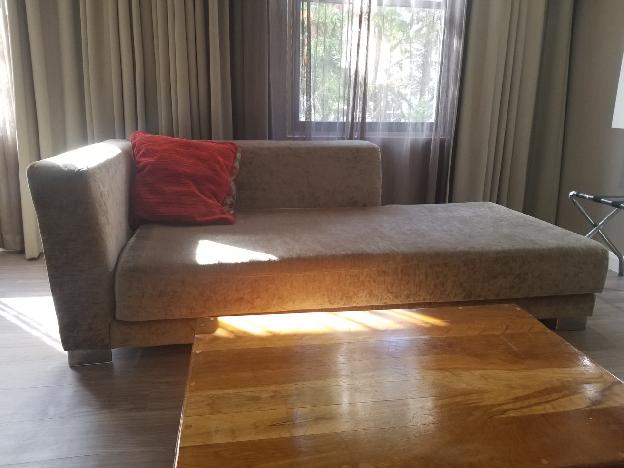a couch with a red pillow in a room with a wood table