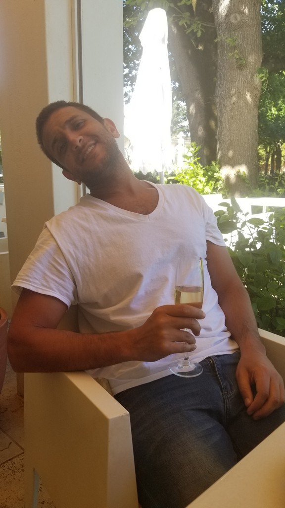 a man sitting on a bench holding a glass of wine