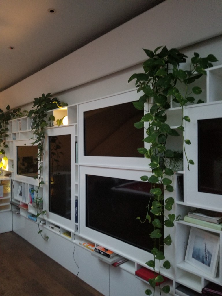 a wall with white shelves and a tv on it