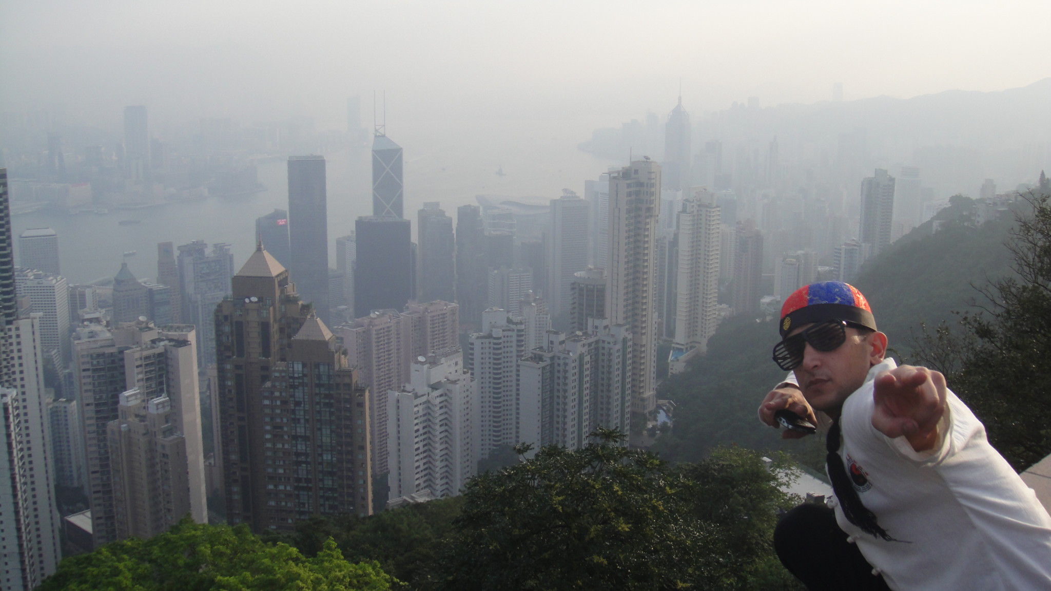 a man standing on a high hill with Victoria Peak in the background