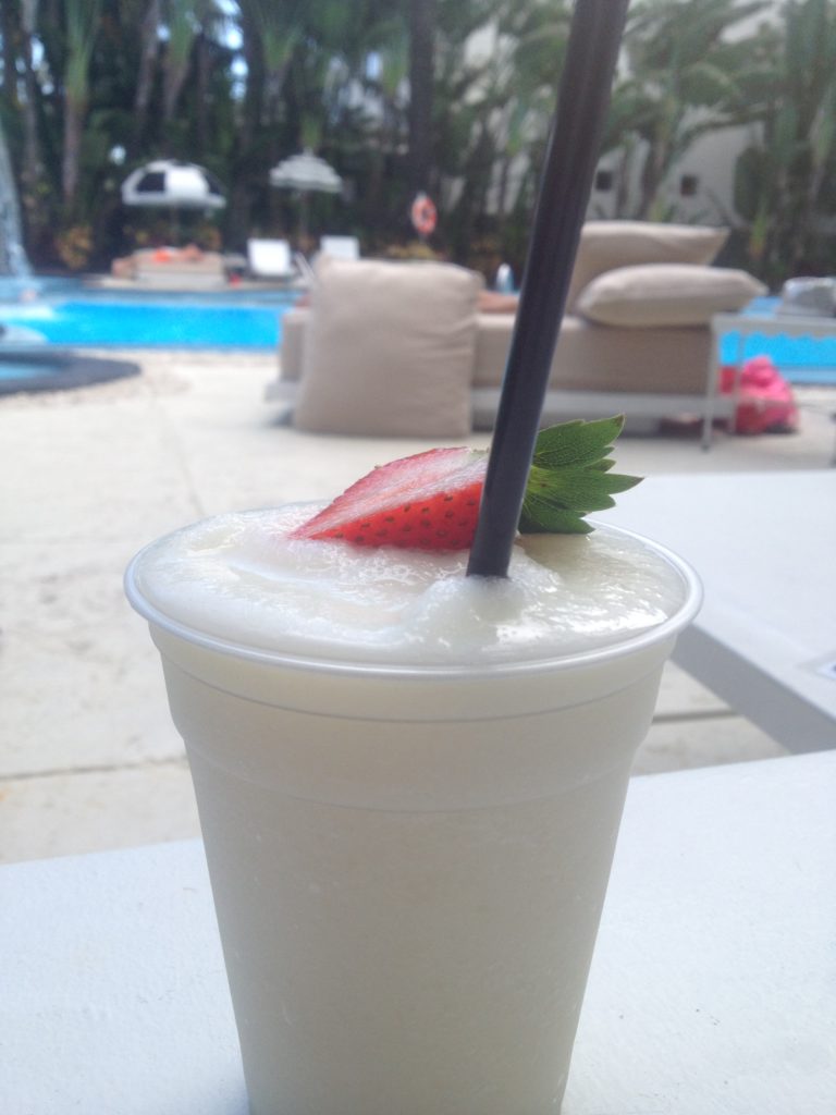 a white drink with straw and a strawberry on top