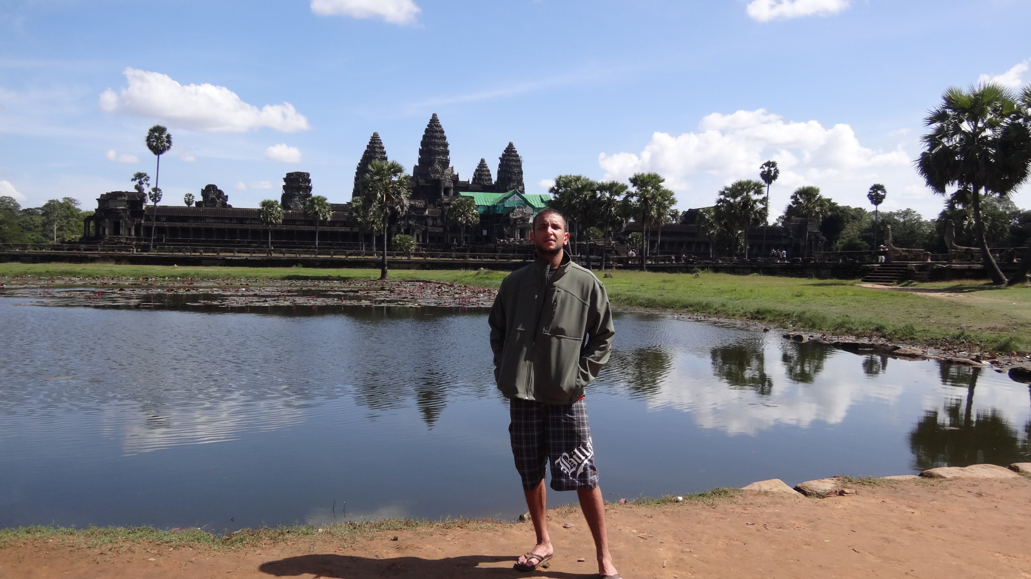 a man standing in front of a body of water with Angkor Wat in the background