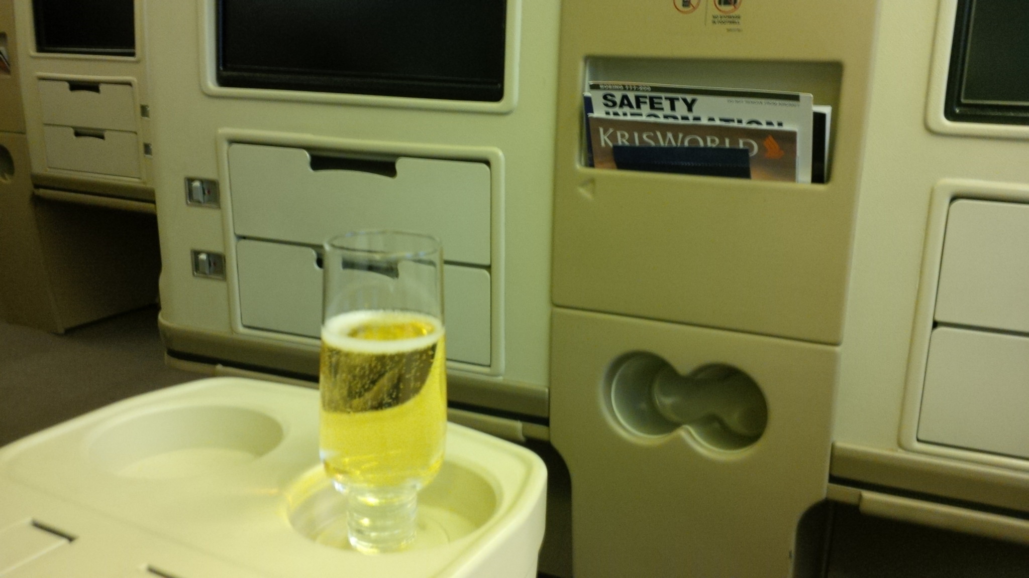 a glass of beer on a tray in a plane