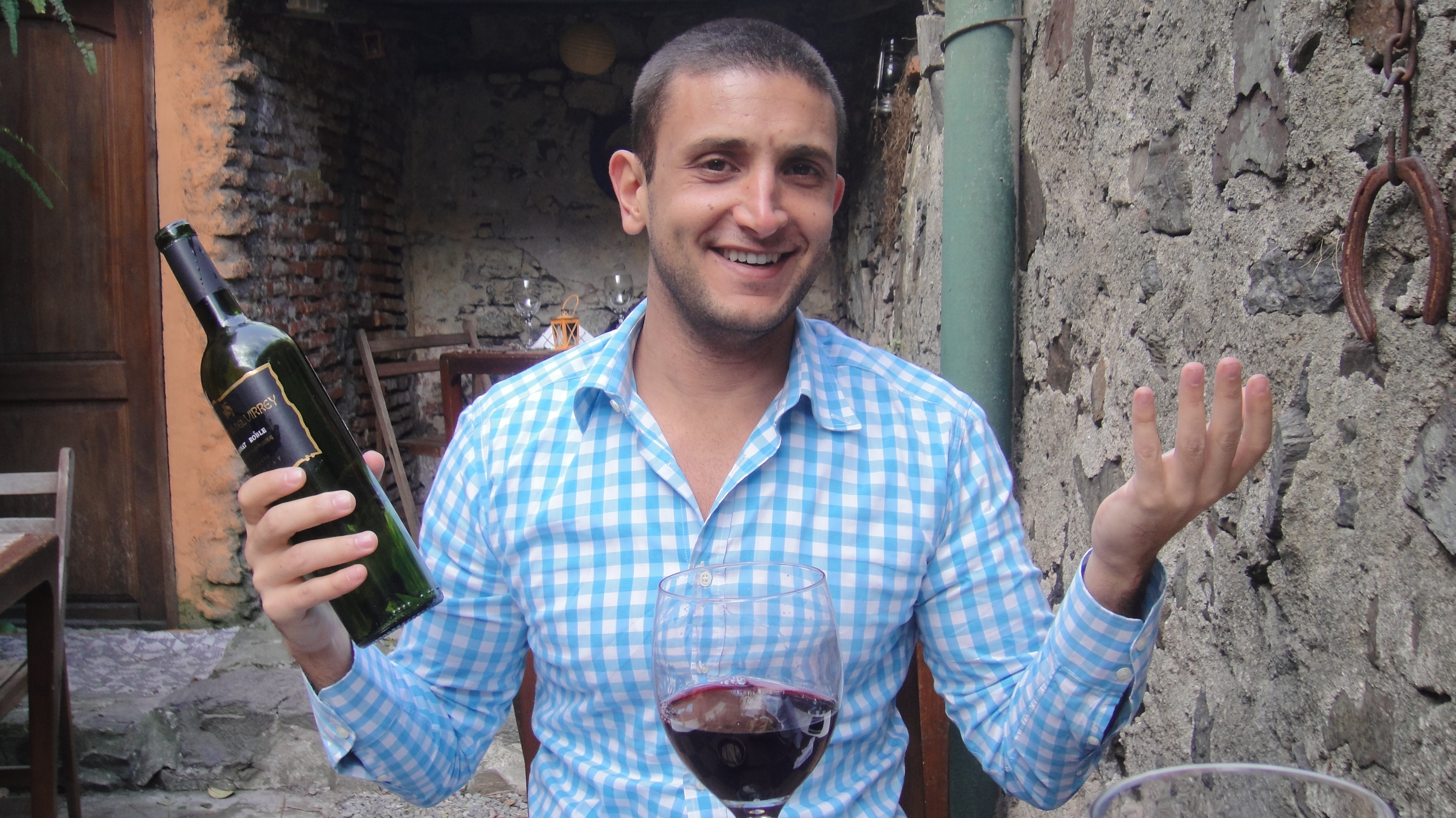 a man holding a glass of wine and a bottle