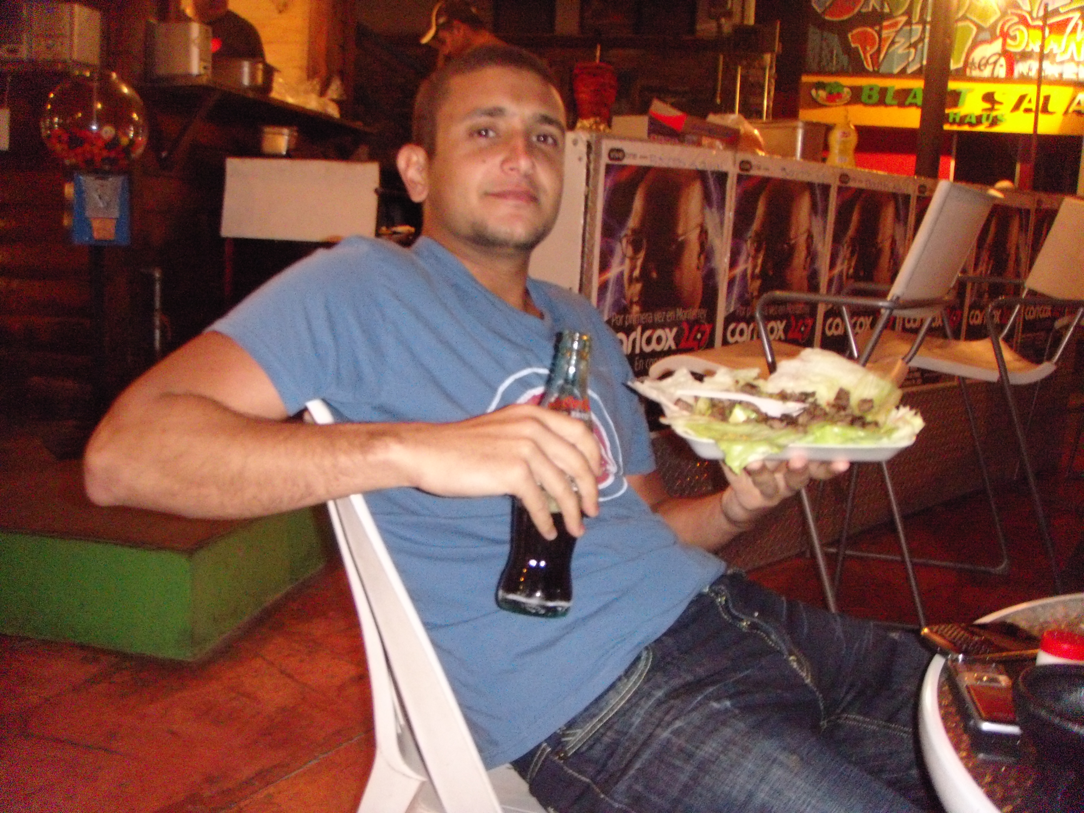 a man sitting in a chair holding a plate of food and a bottle