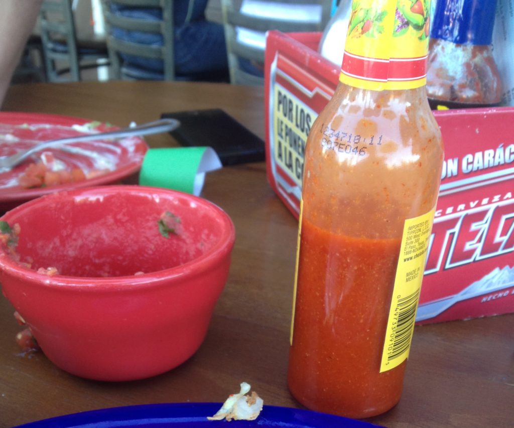 a bottle of hot sauce next to a bowl