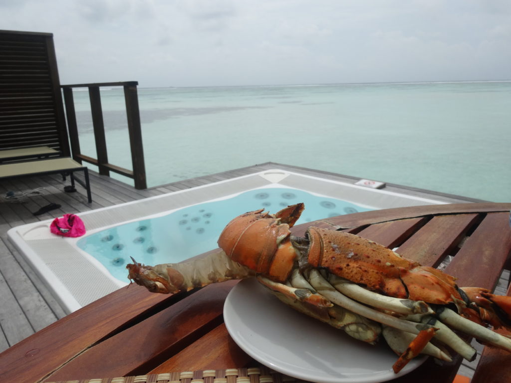 a lobster on a plate on a table by a hot tub