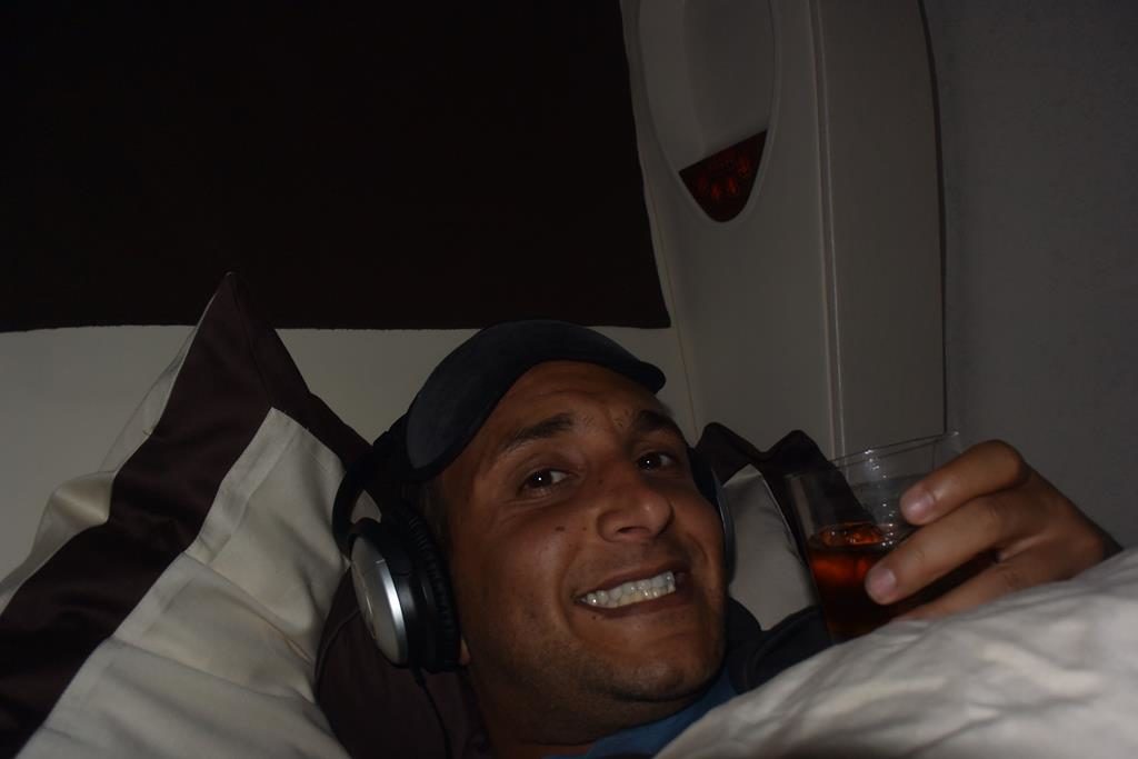 a man lying in bed with headphones and a drink