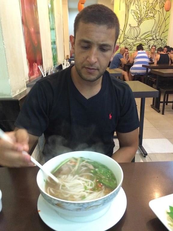 a man sitting at a table eating soup