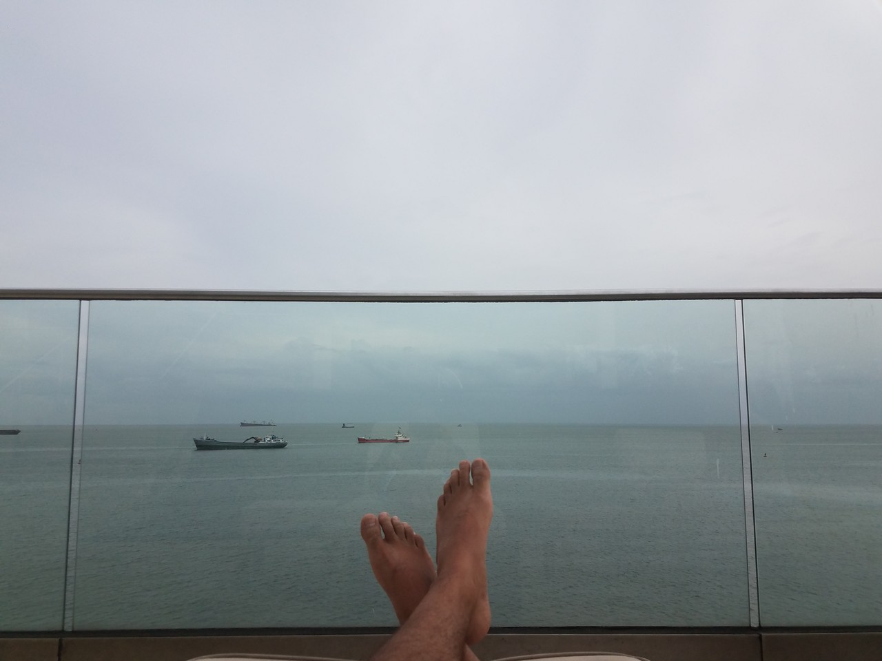 a person's feet on a balcony overlooking water