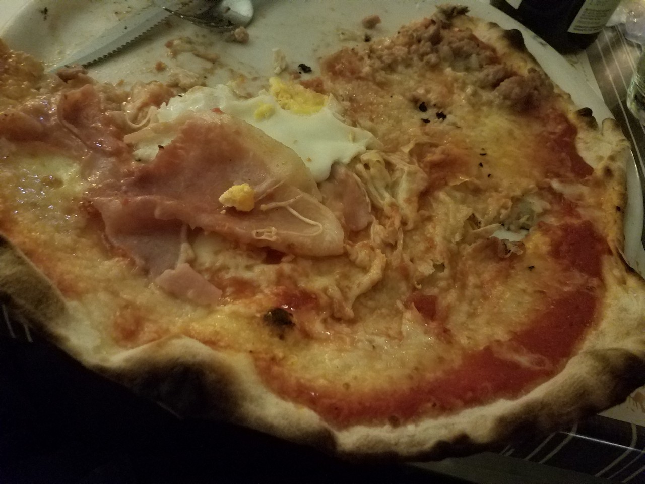a pizza with a broken egg and ham on it