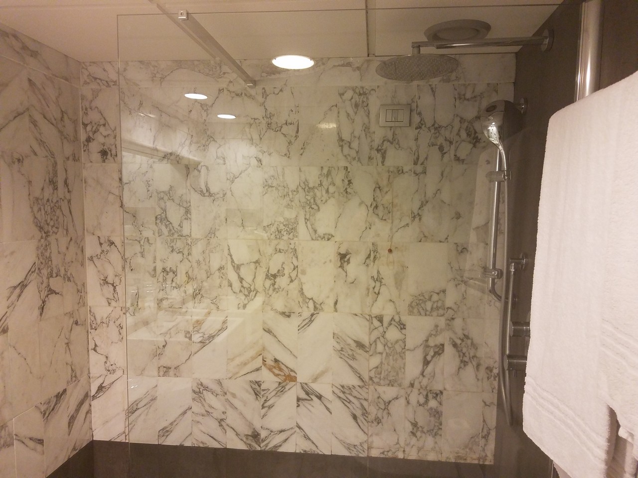 a shower with a white and black marble tile