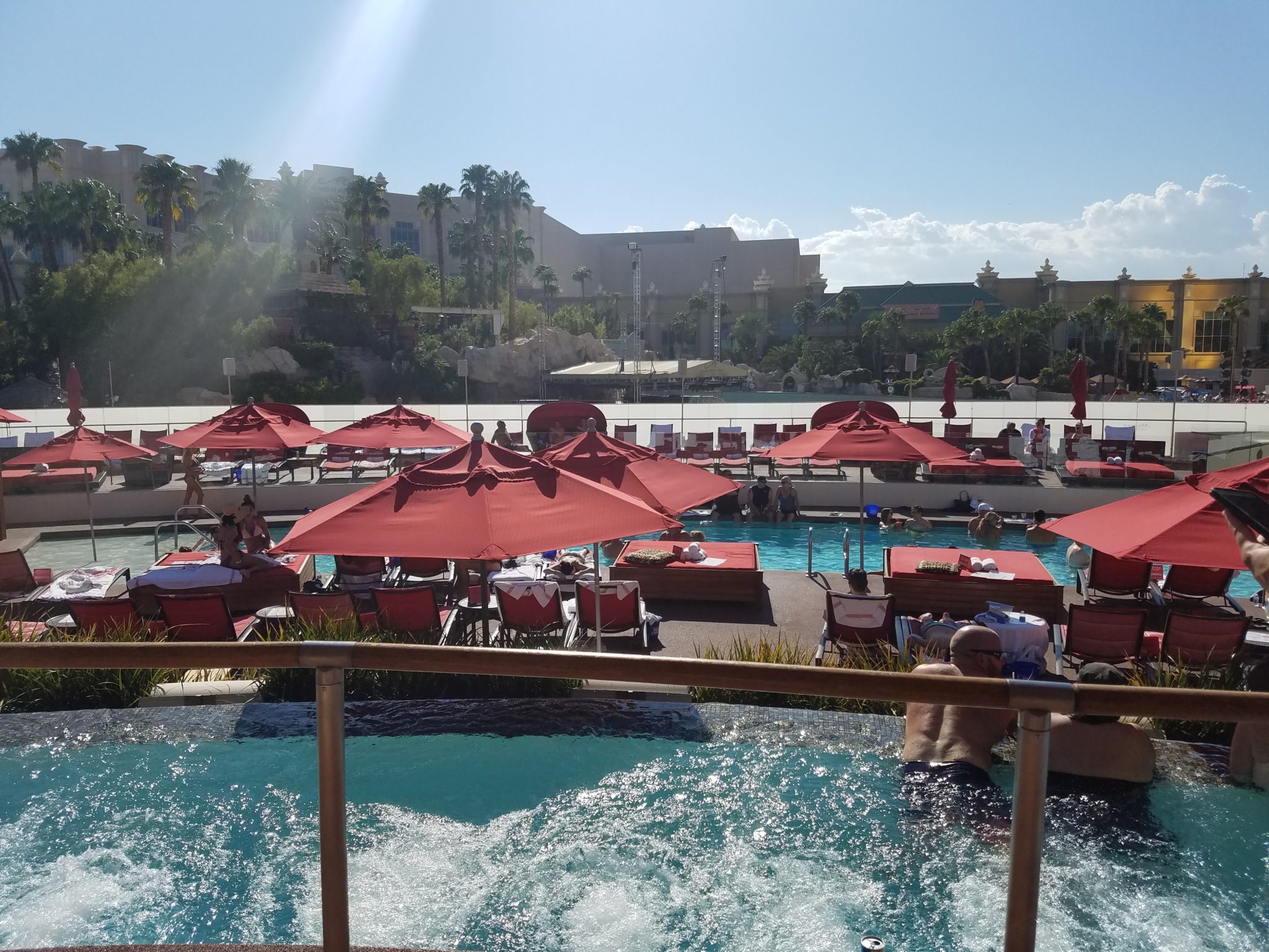 a pool with red umbrellas and people in it