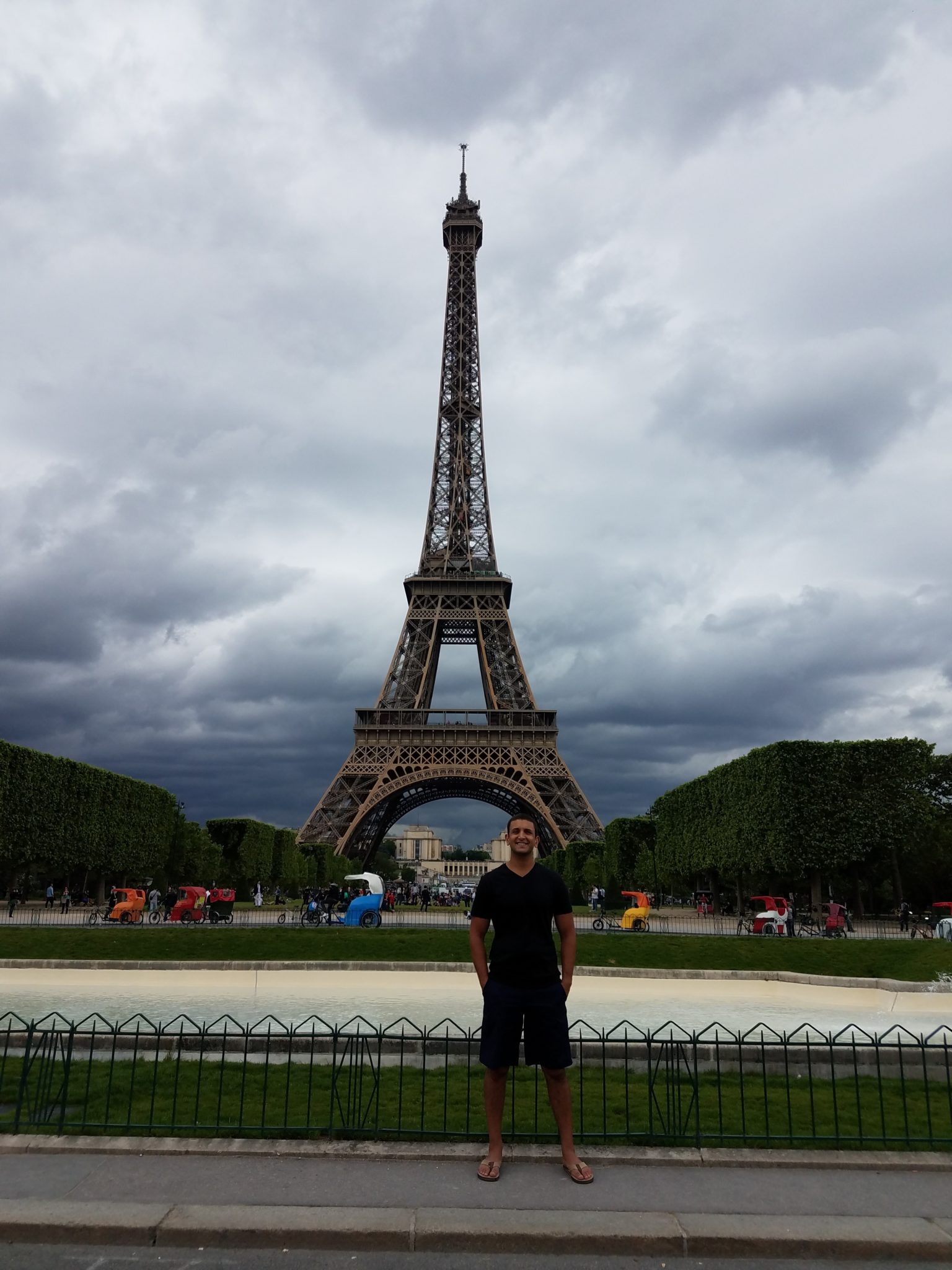 a man standing in front of a tall tower with Eiffel Tower in the background