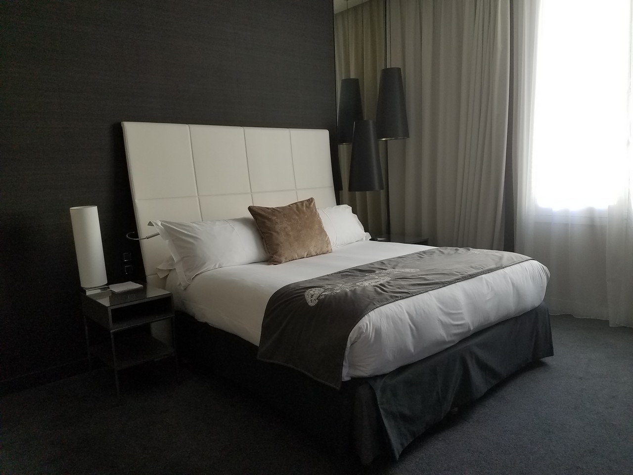 a bed with a white headboard and a black wall