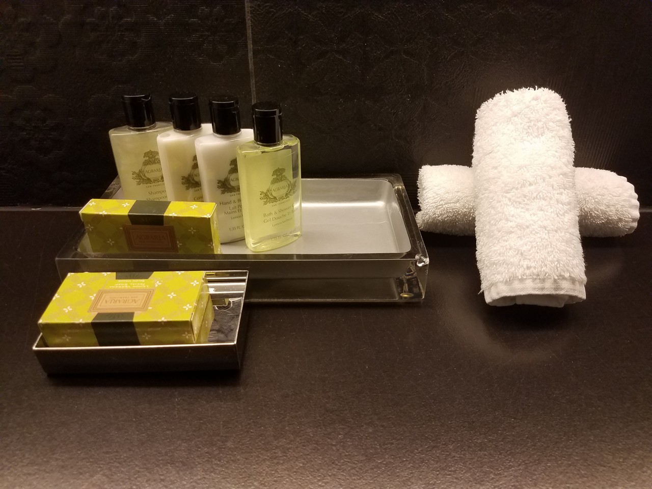 a group of bottles of shampoo and a towel on a tray