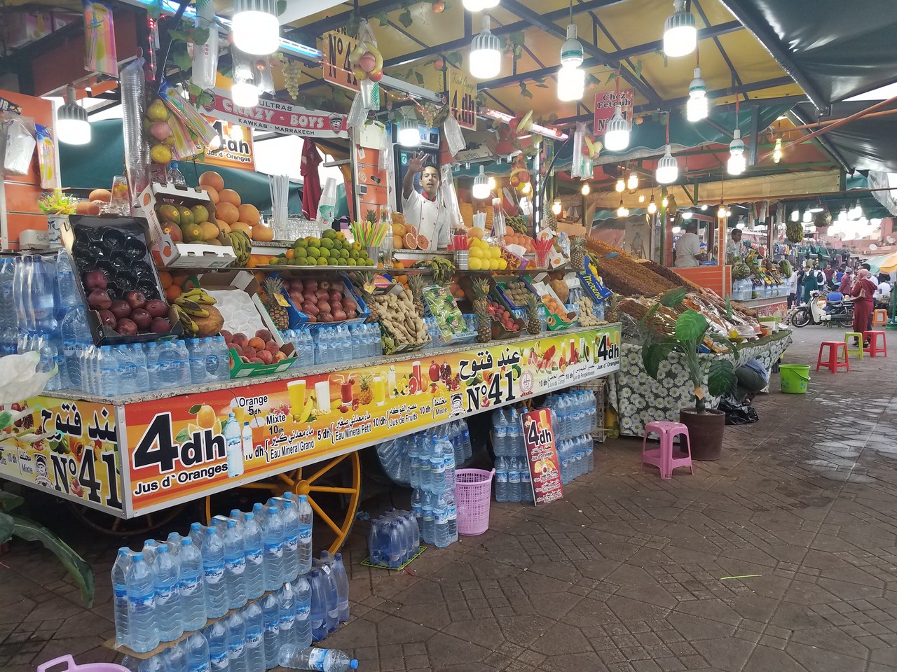 a fruit stand with many bottles of water and other fruits