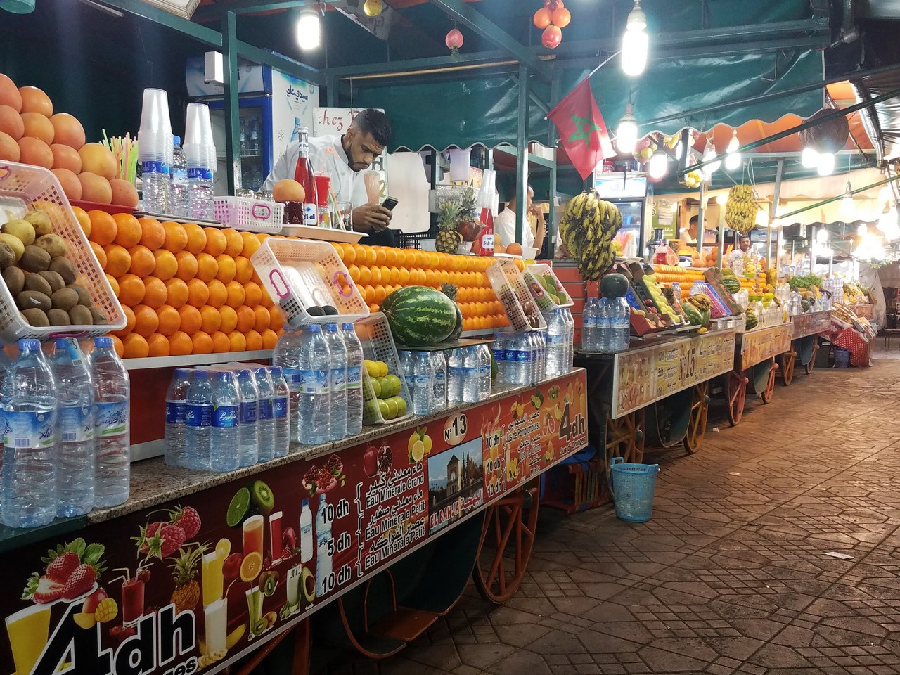 a fruit stand with oranges and water bottles