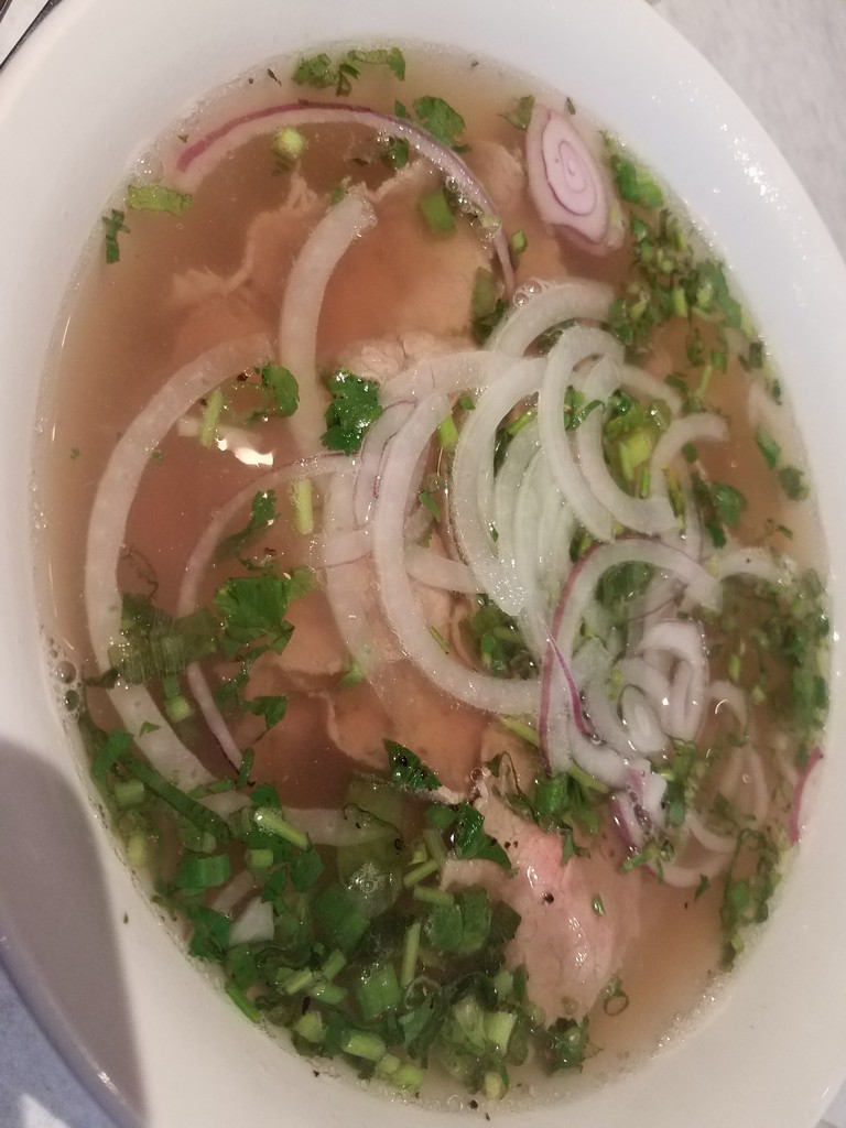 a bowl of soup with onions and herbs