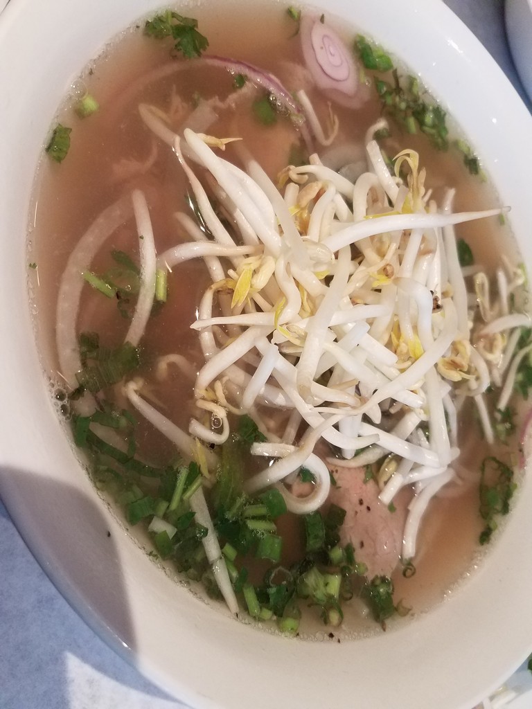 a bowl of soup with sprouts and meat