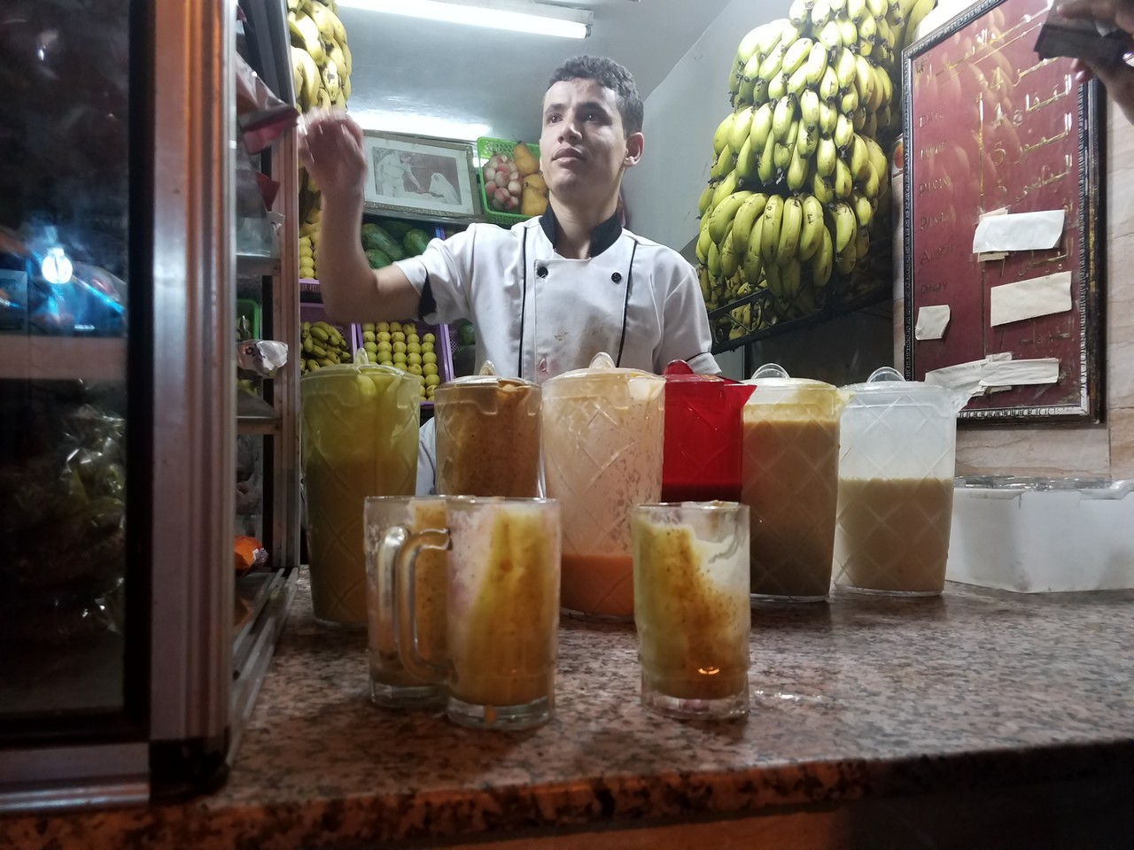 a man standing behind a counter with many glasses of liquid