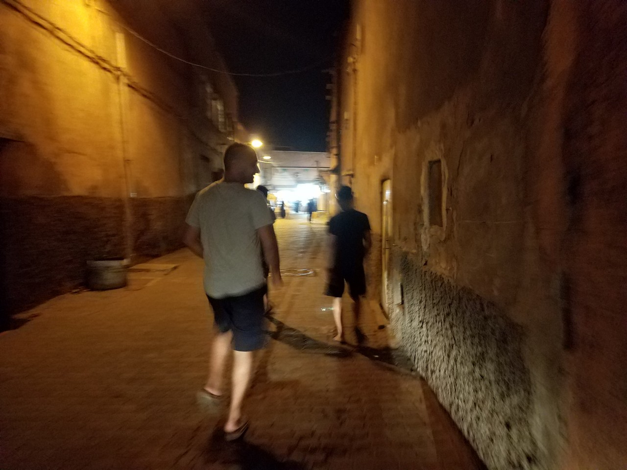 a man walking down a narrow alley at night