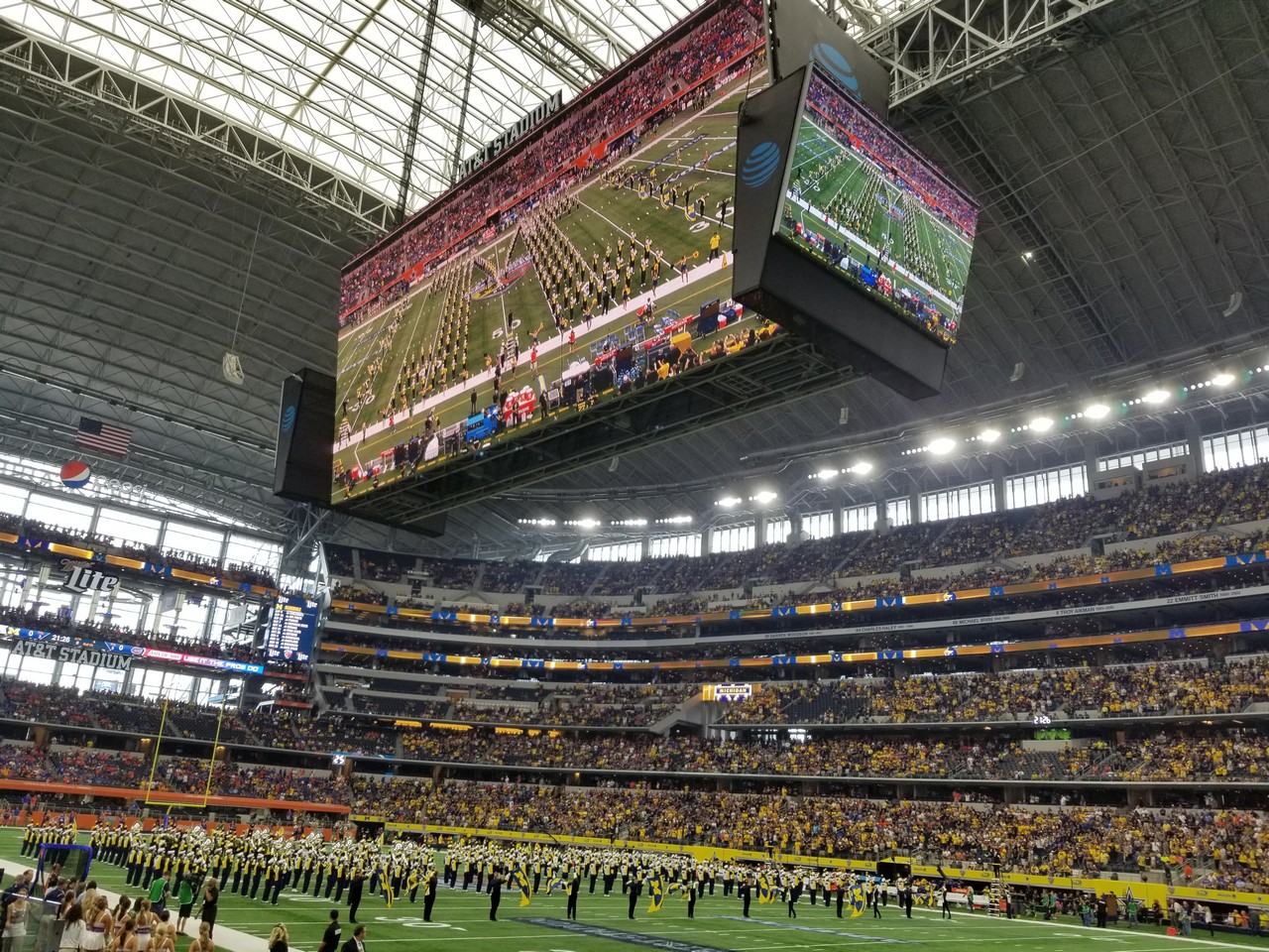 a large screen in a stadium with AT&T Stadium in the background
