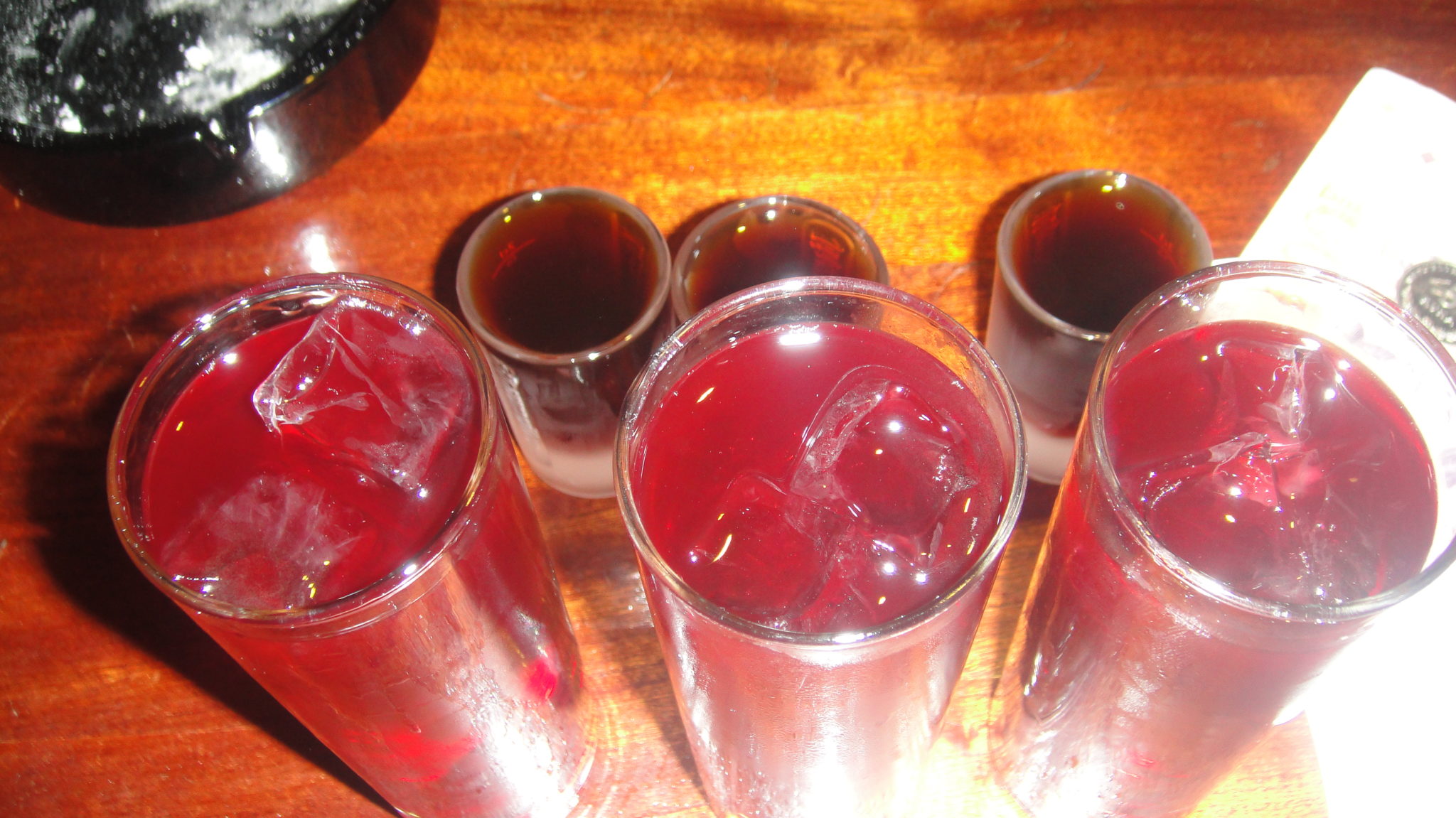 a group of glasses with red liquid and ice
