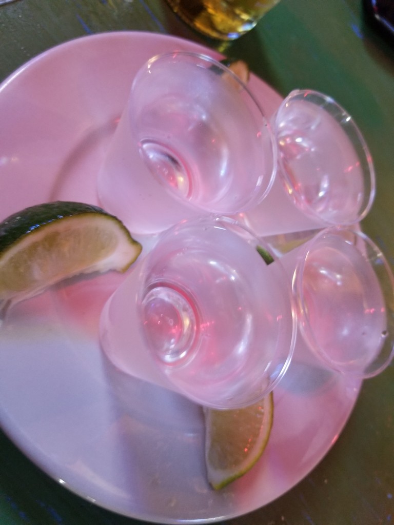 a group of empty shot glasses on a plate with lime wedges