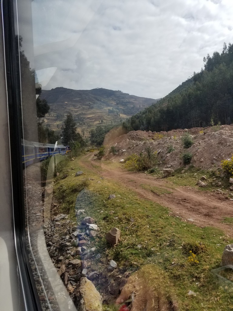 a view of a dirt road through a window of a train