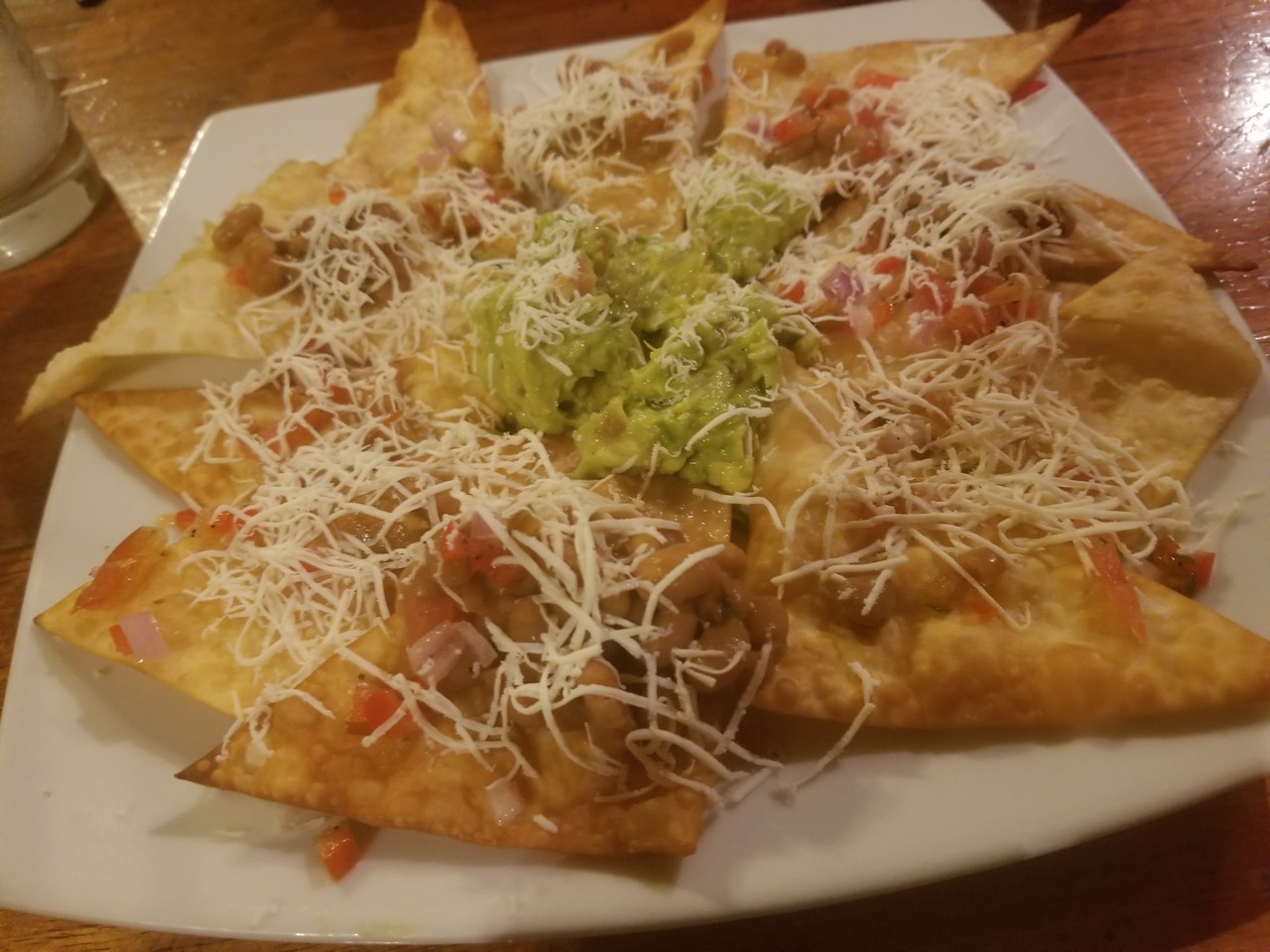 a plate of nachos with guacamole and cheese