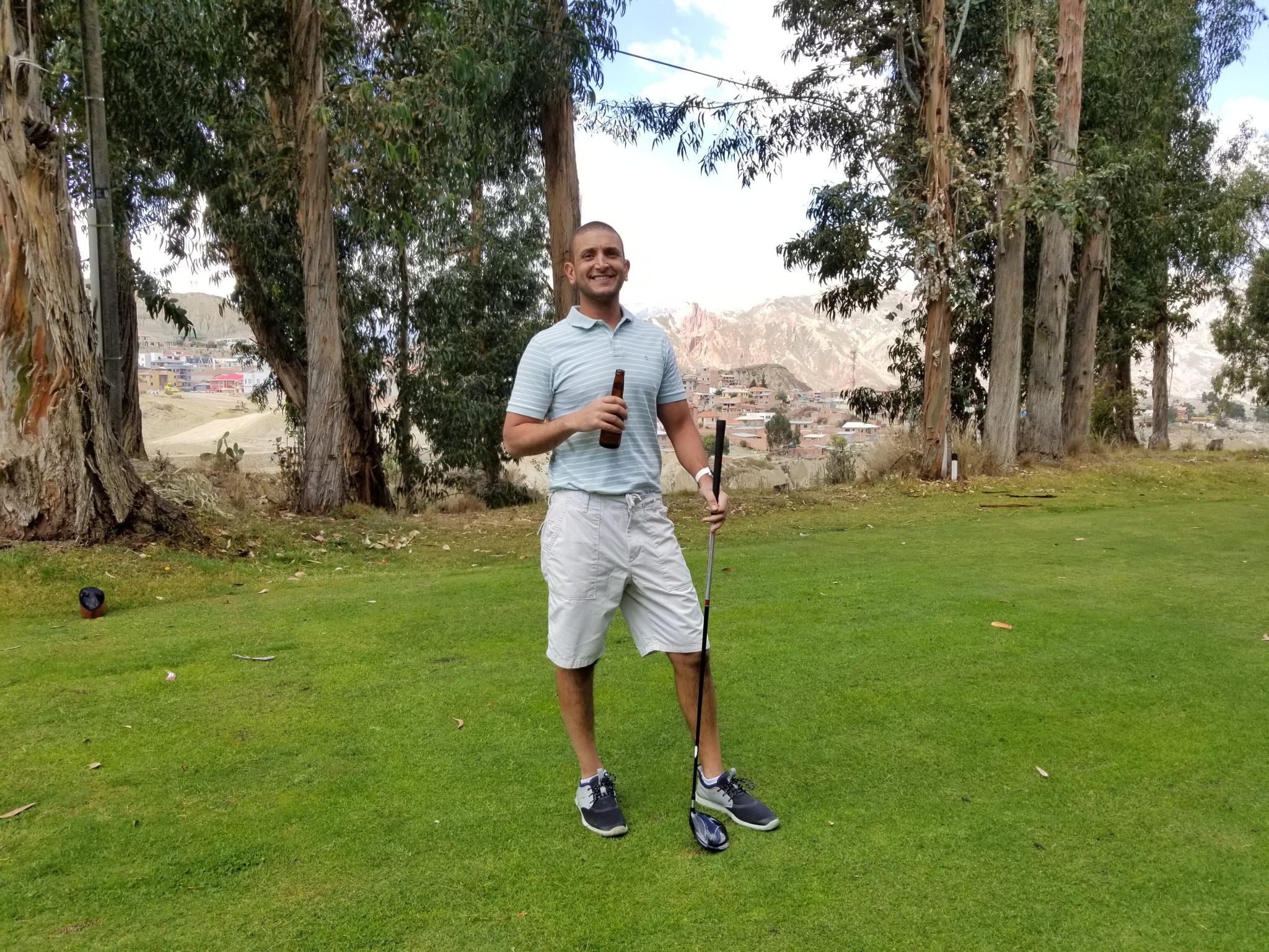 a man holding a golf club and a bottle