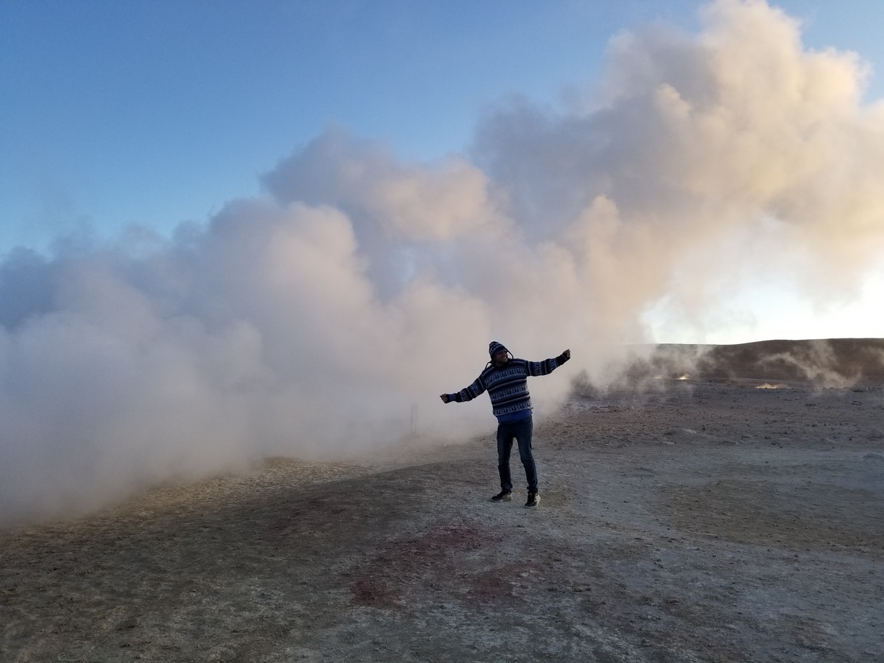 a person standing in a dirt area with smoke coming out of it