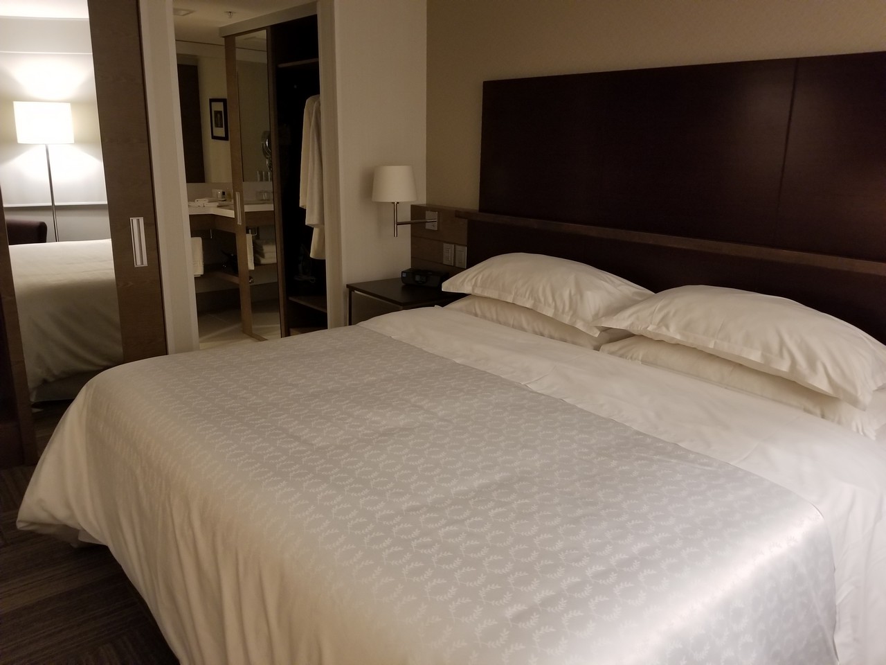 a bed with white sheets and pillows in a hotel room