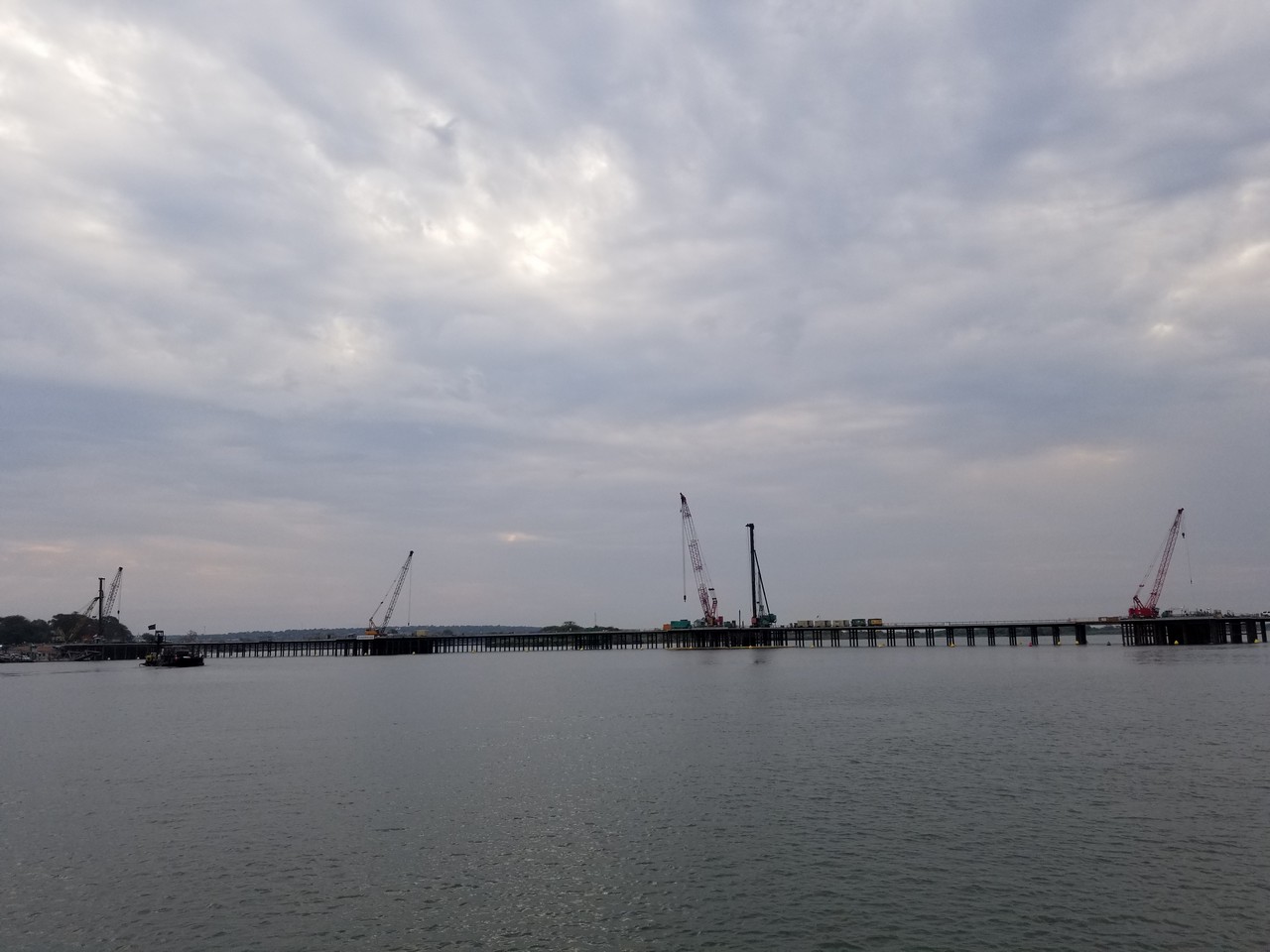 a long bridge over water with cranes