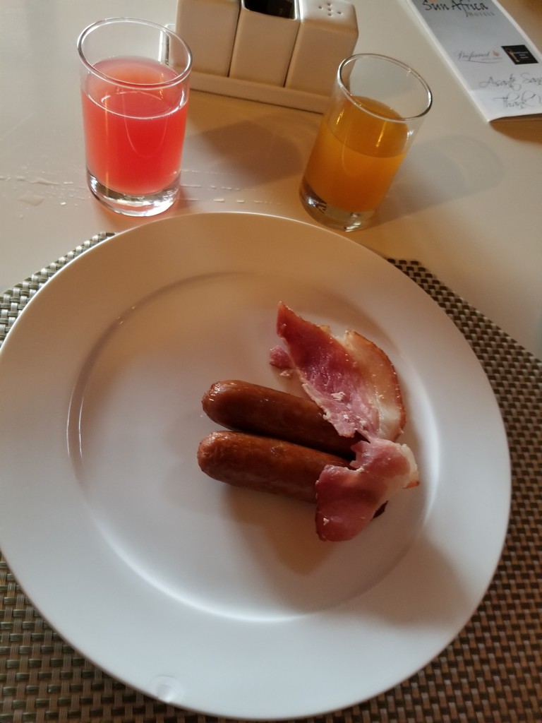a plate of sausages and bacon on a table