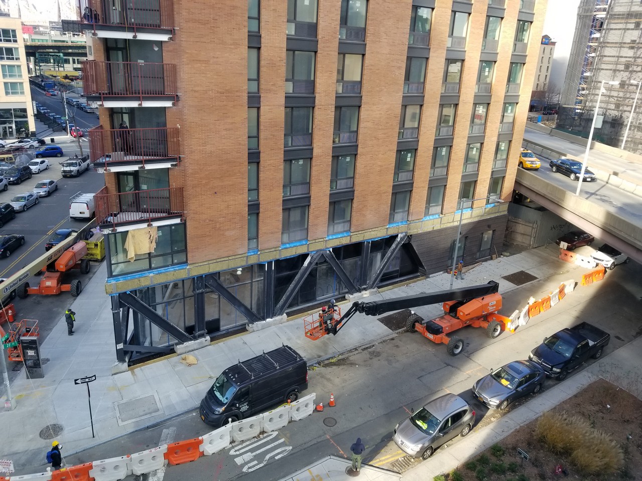 a construction site with a crane and cars parked on the side of a road