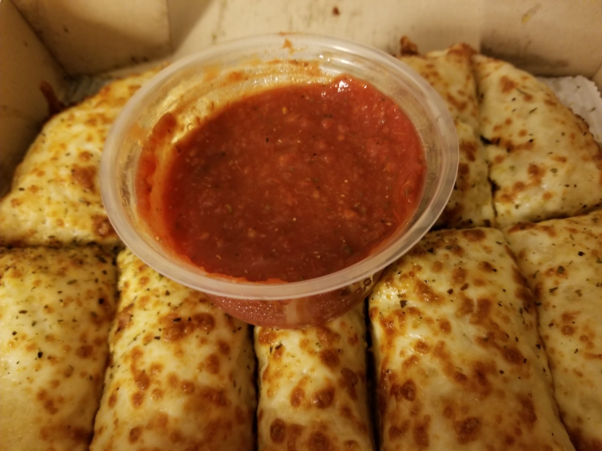 a container of sauce on a pizza