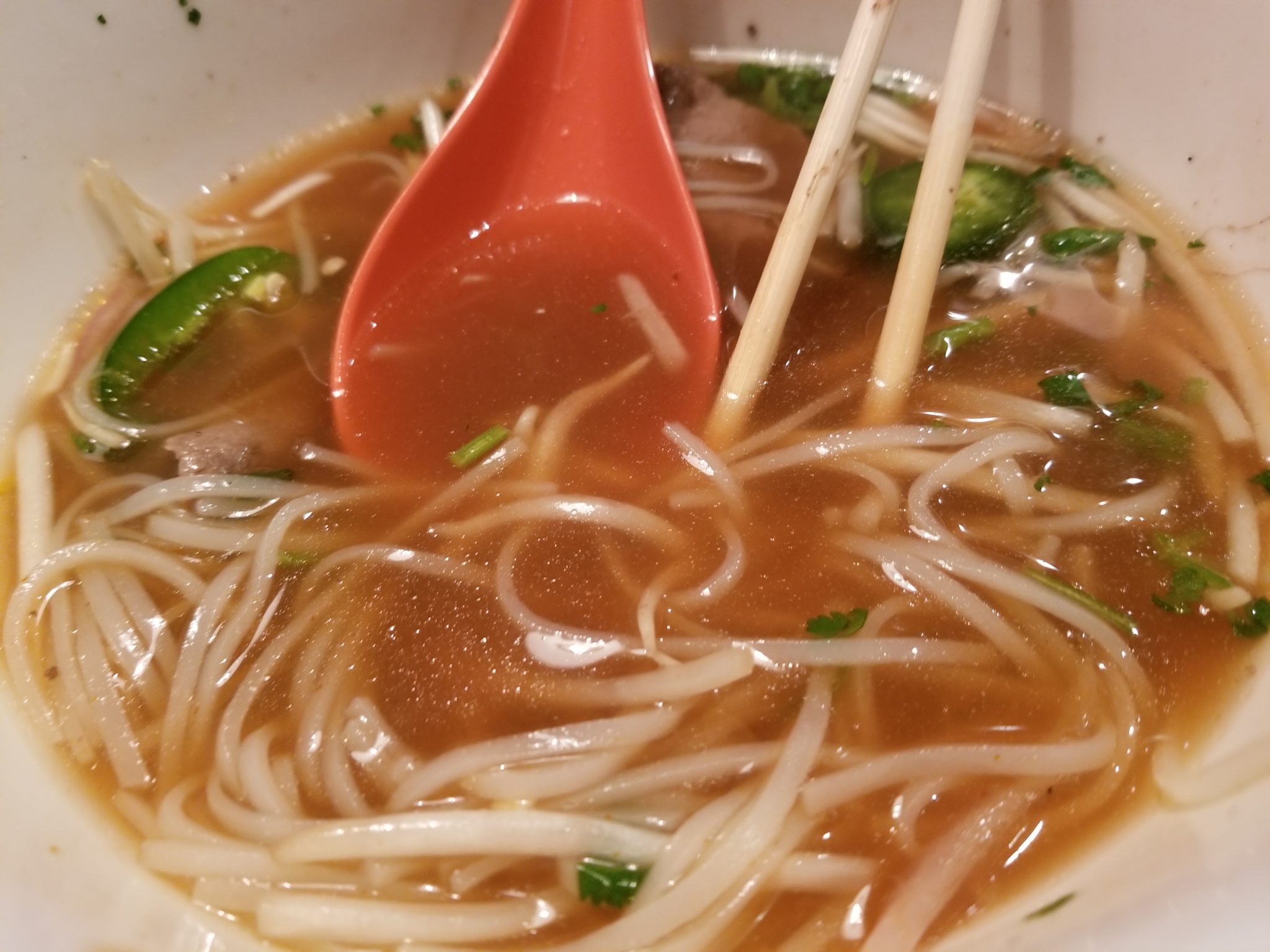 a bowl of soup with chopsticks and noodles