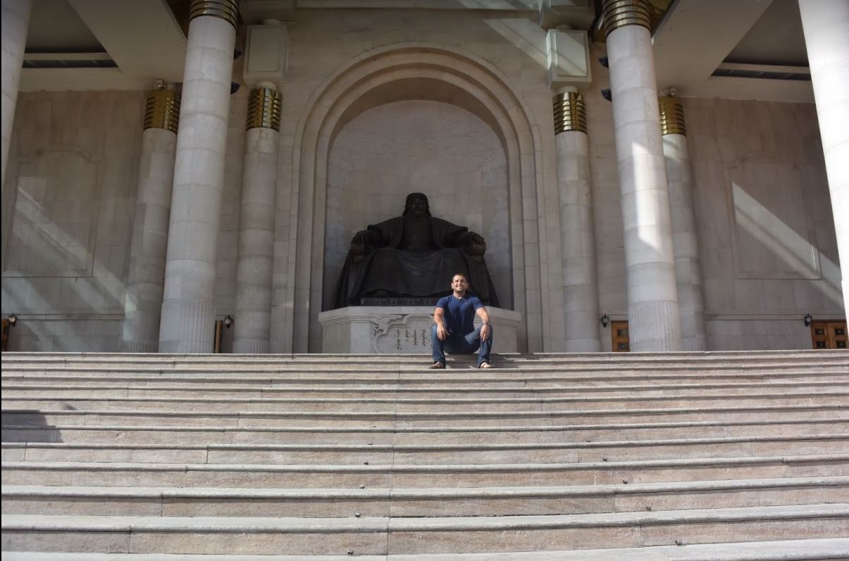 a man posing on stairs in front of a statue