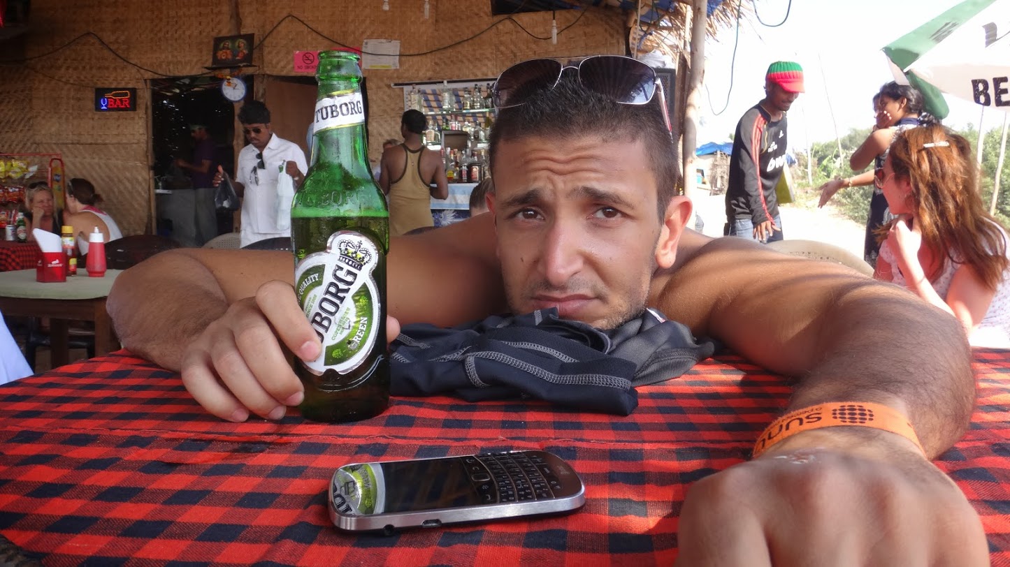 a man sitting at a table with a beer bottle and cell phone