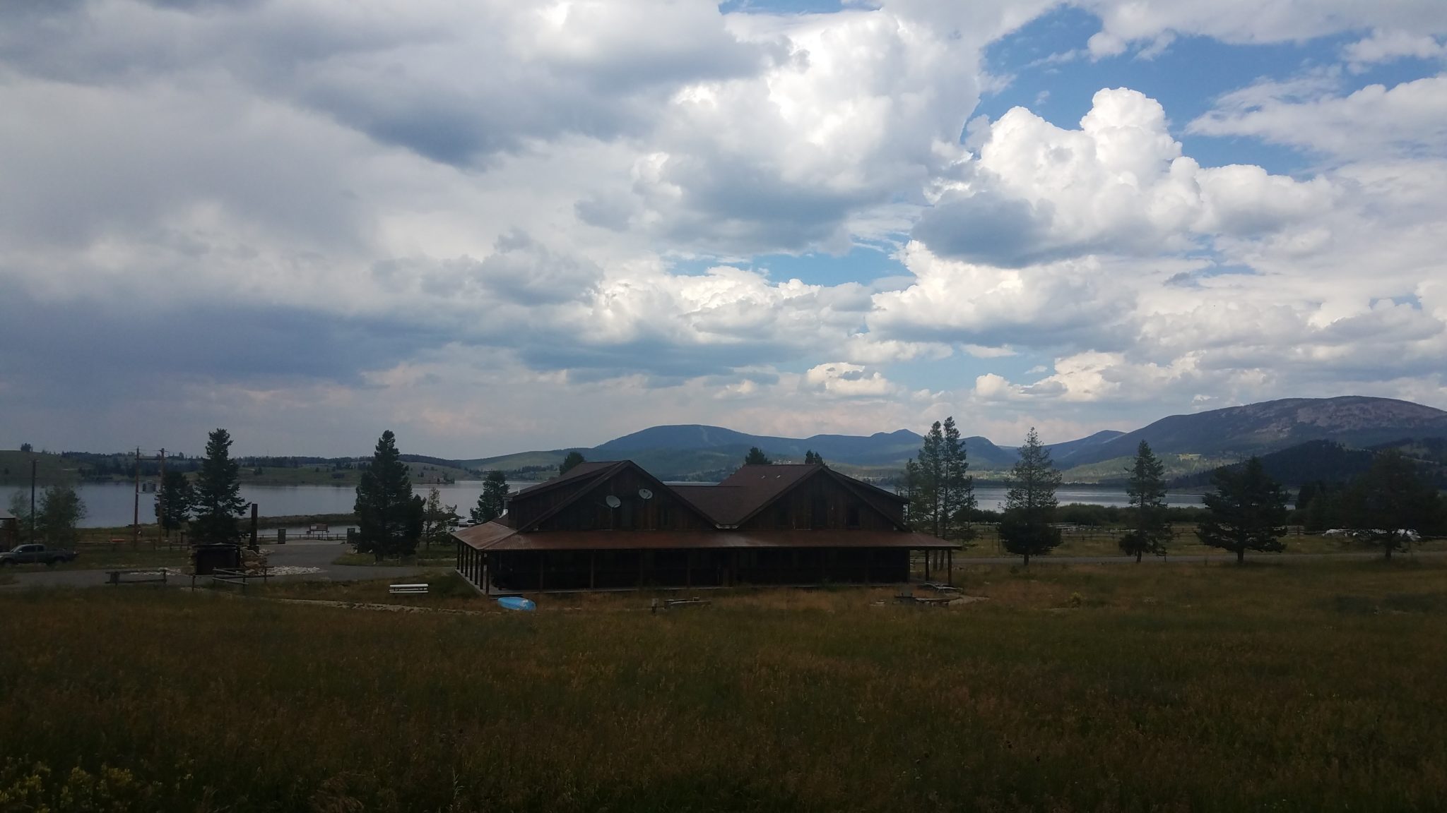 a building in a field with a lake and mountains in the background