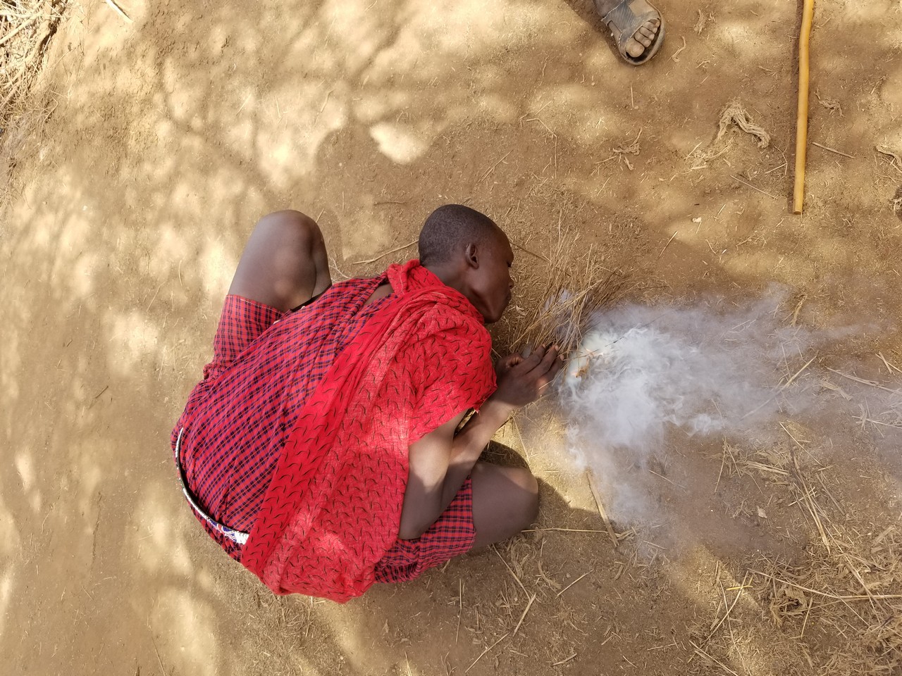 a man in a red dress kneeling on the ground with smoke