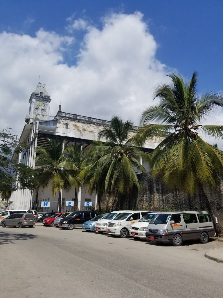 a building with palm trees and cars parked in front of it