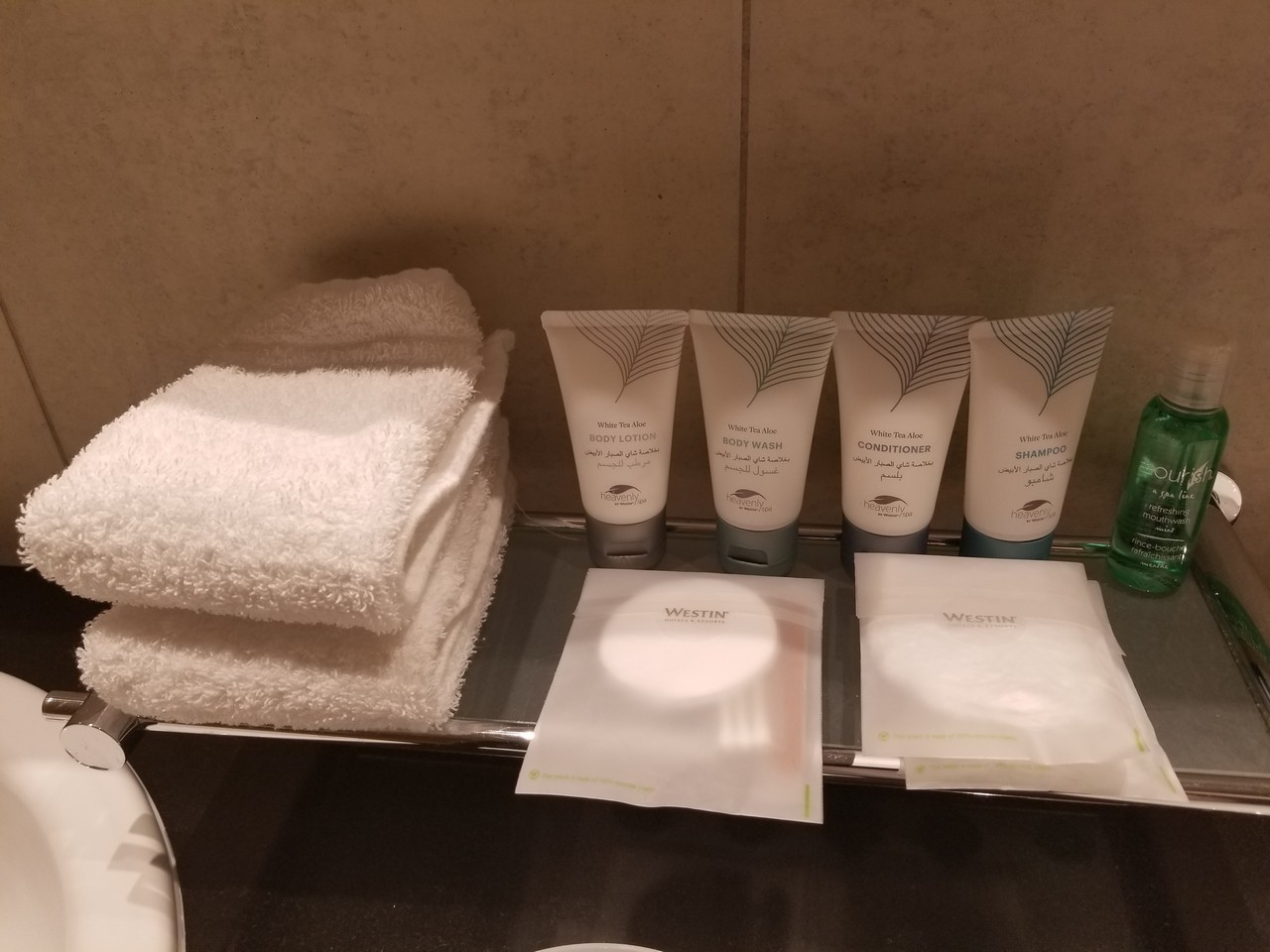 a group of white towels and a few white tubes on a shelf