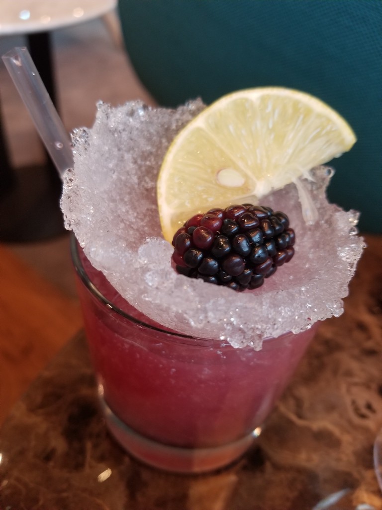 a drink with a lemon slice and a blackberry
