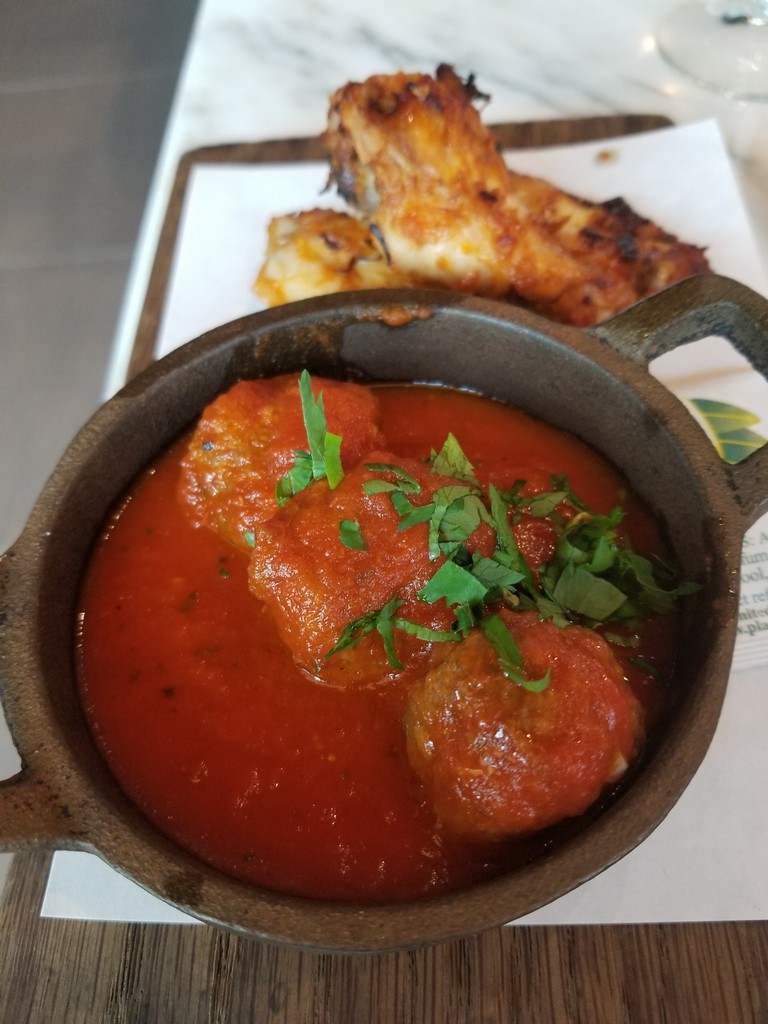 a bowl of soup with meatballs and parsley